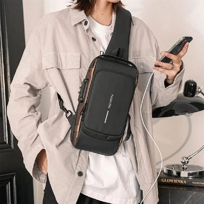 Person wearing a black crossbody bag holding a phone, with a neutral background.  Upgrade your everyday style with a modern men's crossbody sling bag. Designed for travel and daily use, featuring a sleek design, adjustable strap and practical storage compartments. Shop your ideal sling bag today.
